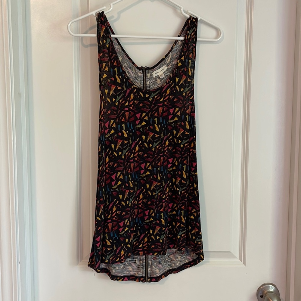 Silence and noise tank with gold zipper detail and black geometric pattern.